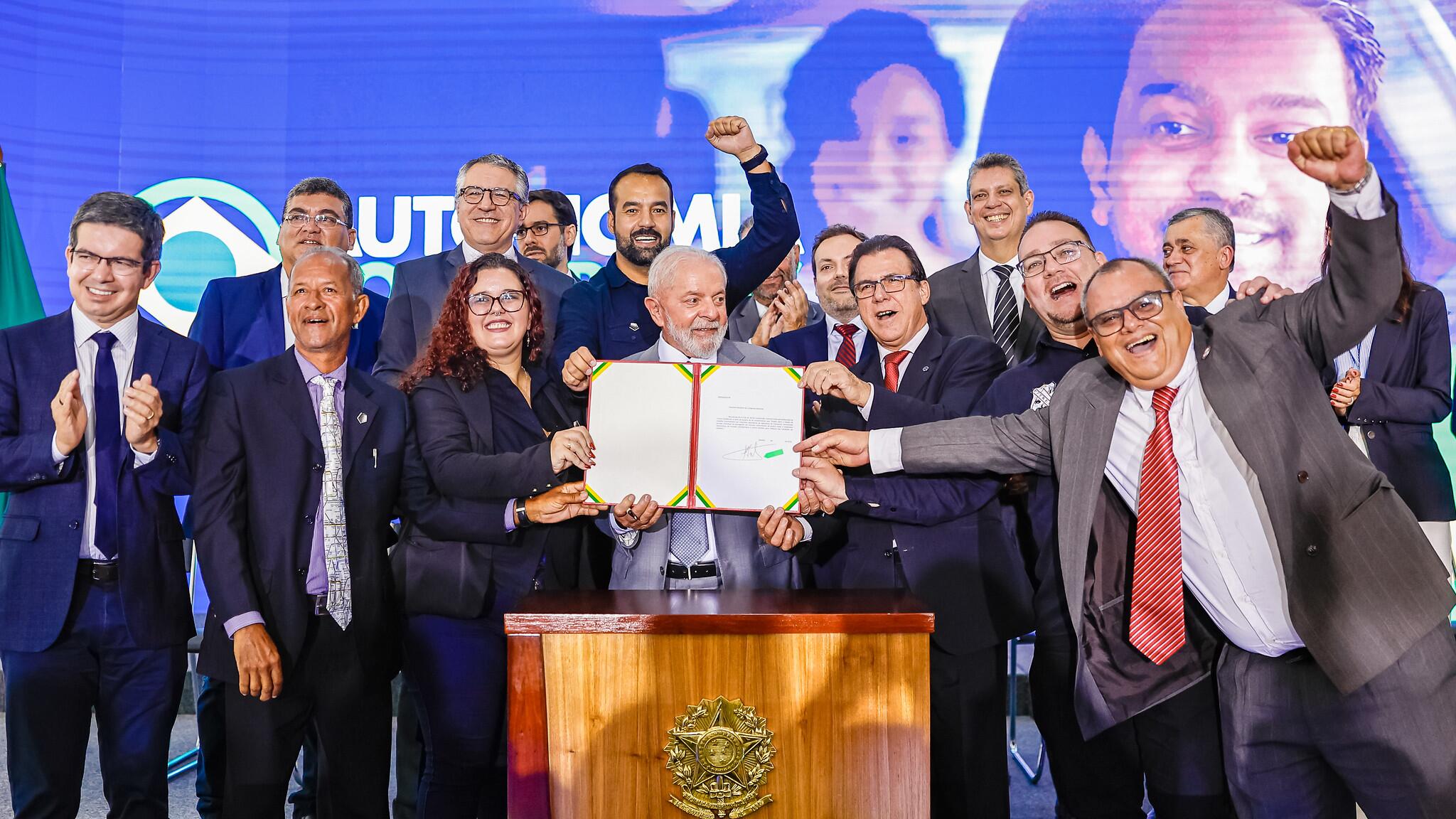 Foto mostra Lula segurando projeto assinado junto do ministro do Trabalho, Luís Marinho (PT), e outros membros do governo