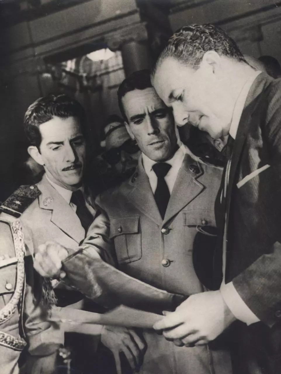 Dois militares fardados e o presidente João Goulart olham para um documento.