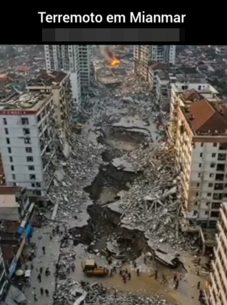 Fotografia aérea de uma cidade devastada por um terremoto. Um grande rasgo no solo atravessa o centro da imagem, cercado por escombros de prédios desmoronados. Edifícios altos ainda de pé mostram sinais de destruição, com janelas quebradas e estruturas comprometidas. Ao fundo, um incêndio pode ser visto entre os destroços. Há pessoas e veículos de resgate no local.