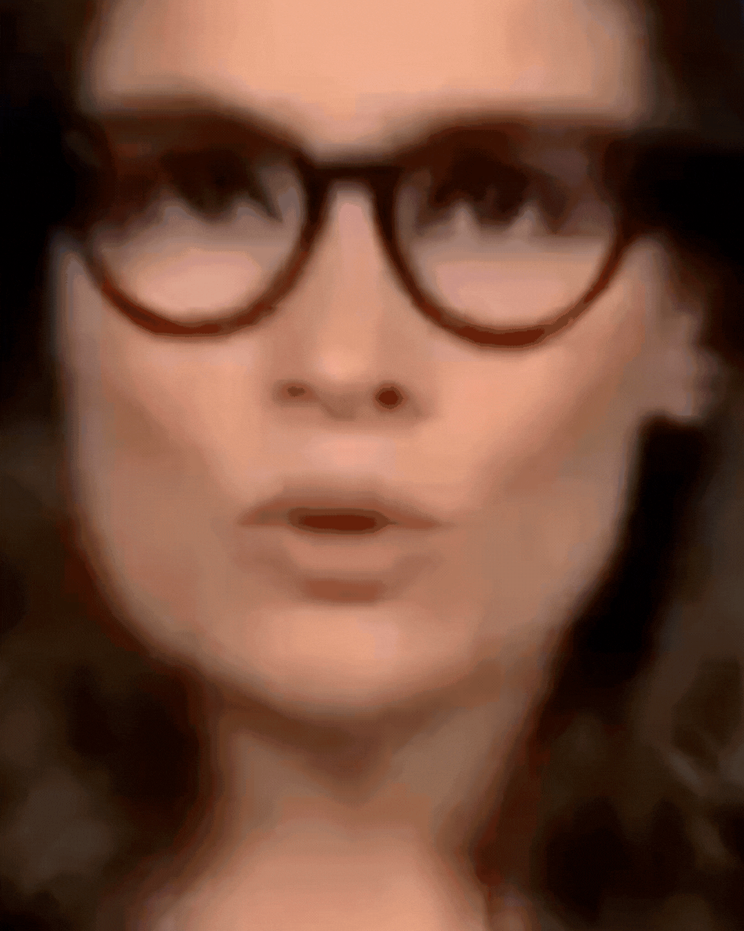Gif de um trecho do vídeo que mostra a apresentadora do Jornal Nacional Renata Vasconcellos — uma mulher branca, de cabelos castanhos escuros na altura dos ombros, que usa óculos de armação preta e veste um blazer escuro. Ao fundo, vê-se um cenário azul com o logotipo do Jornal Nacional, representado pelas letras ‘JN’ em azul claro com contorno vermelho e um mapa-mundi.