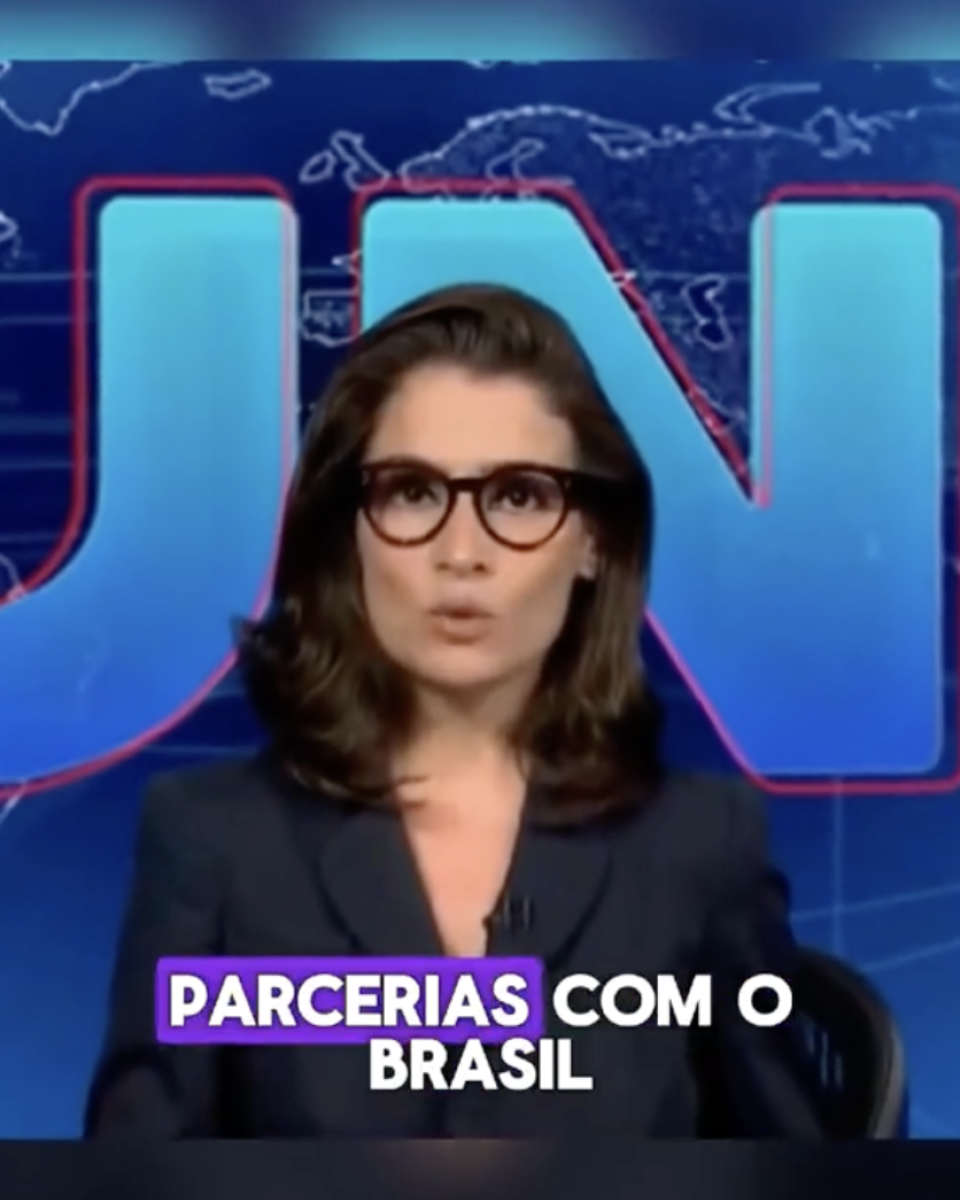 Print de uma publicação no TikTok mostra a apresentadora do Jornal Nacional Renata Vasconcellos — uma mulher branca de cabelos castanhos escuros na altura dos ombros, que usa óculos de armação preta e veste um blazer escuro. Ao fundo, vê-se um cenário azul com o logotipo do Jornal Nacional, representado pelas letras ‘JN’ em azul claro com contorno vermelho e um mapa-mundi.