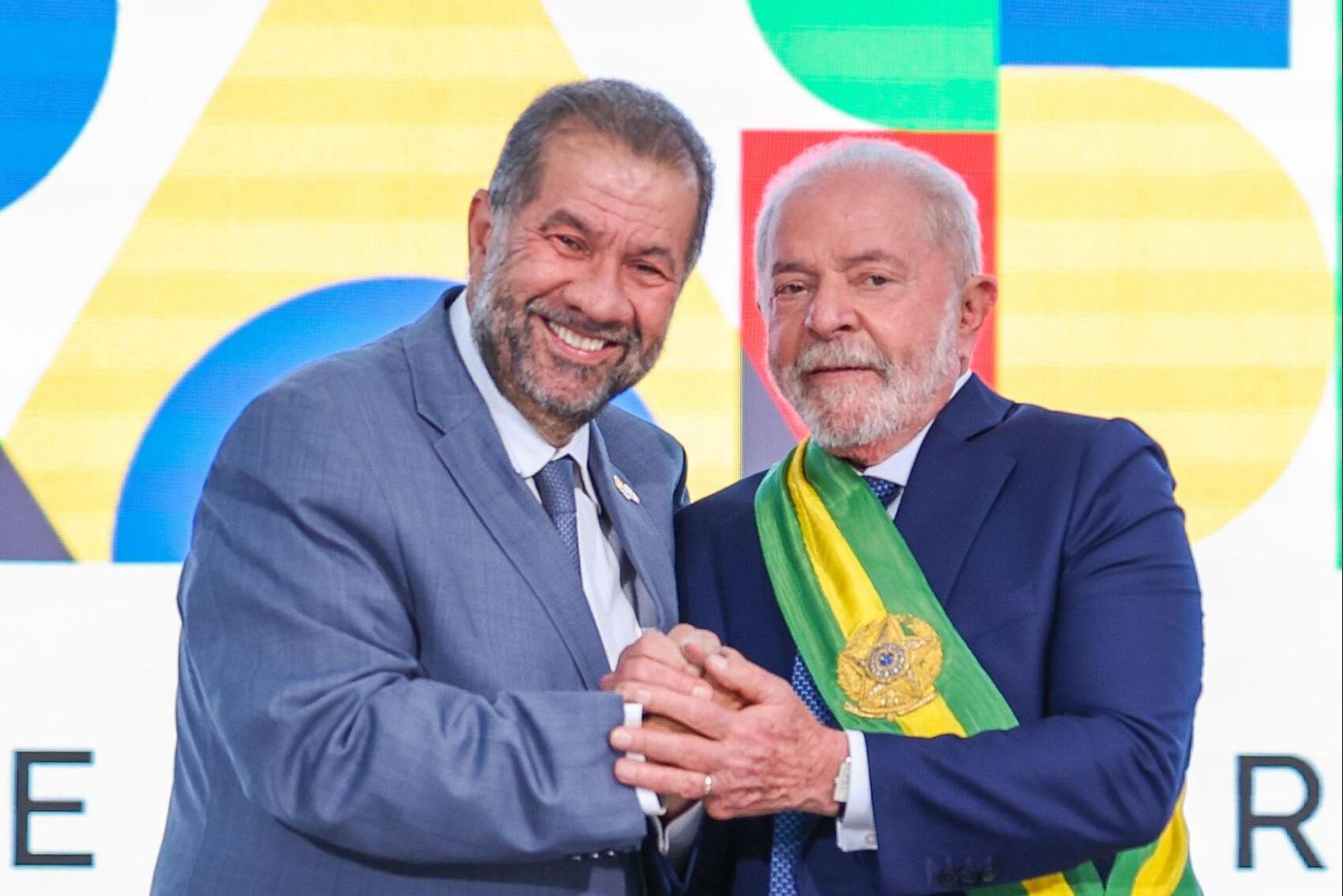 Foto mostra Lula (à dir.) — homem de pele branca e cabelo e barba grisalhos que usa um terno azul-marinho e a faixa de presidente da República nas cores verde e amarelo — ao lado de Carlos Lupi (à esq.) — homem branco de cabelo e barba grisalhos que usa um terno azul claro (Ricardo Stuckert/PR)