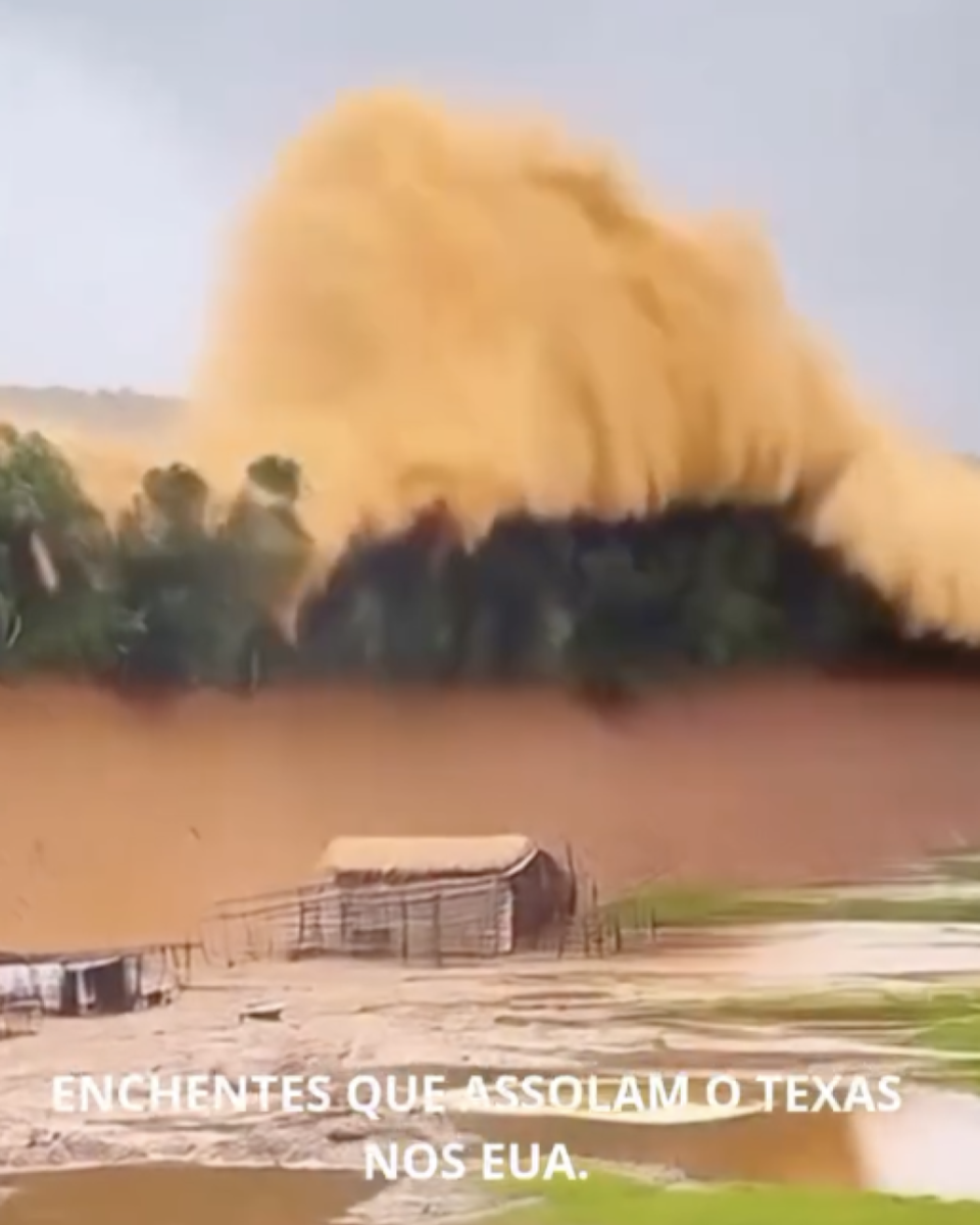 Imagem mostra uma grande onda de água barrenta se aproximando de uma área rural alagada, com vegetação ao fundo e estruturas submersas em primeiro plano. Na parte inferior da imagem, há um texto em letras maiúsculas que diz: ‘ENCHENTES QUE ASSOLAM O TEXAS NOS EUA.’