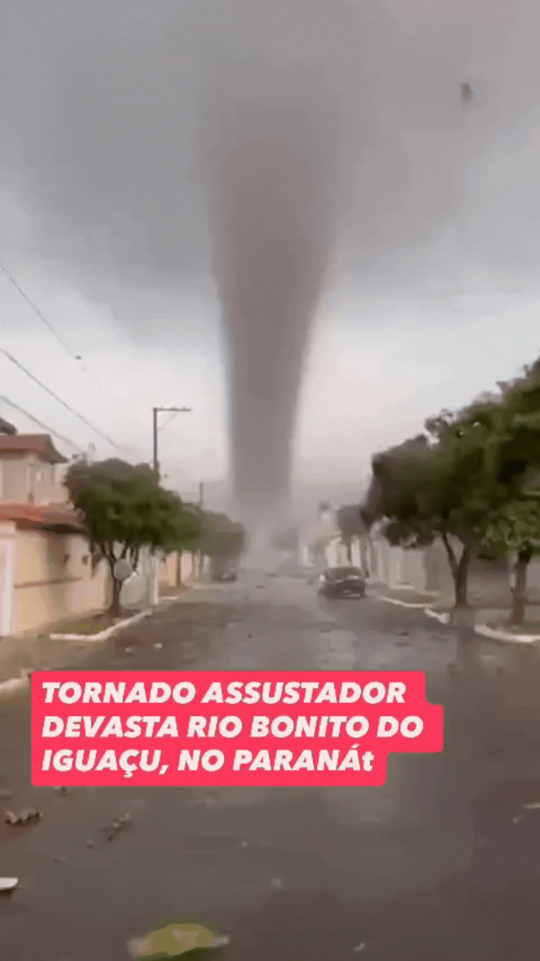 Animação mostra um vídeo gerado por inteligência artificial que simula um tornado passando por uma cidade. Ao centro, é possível perceber que o fenômeno não se desloca e não danifica veículos e casas próximas ao funil de vento. Objetos que se assemelham a folhagens também surgem e desaparecem da cena. 
