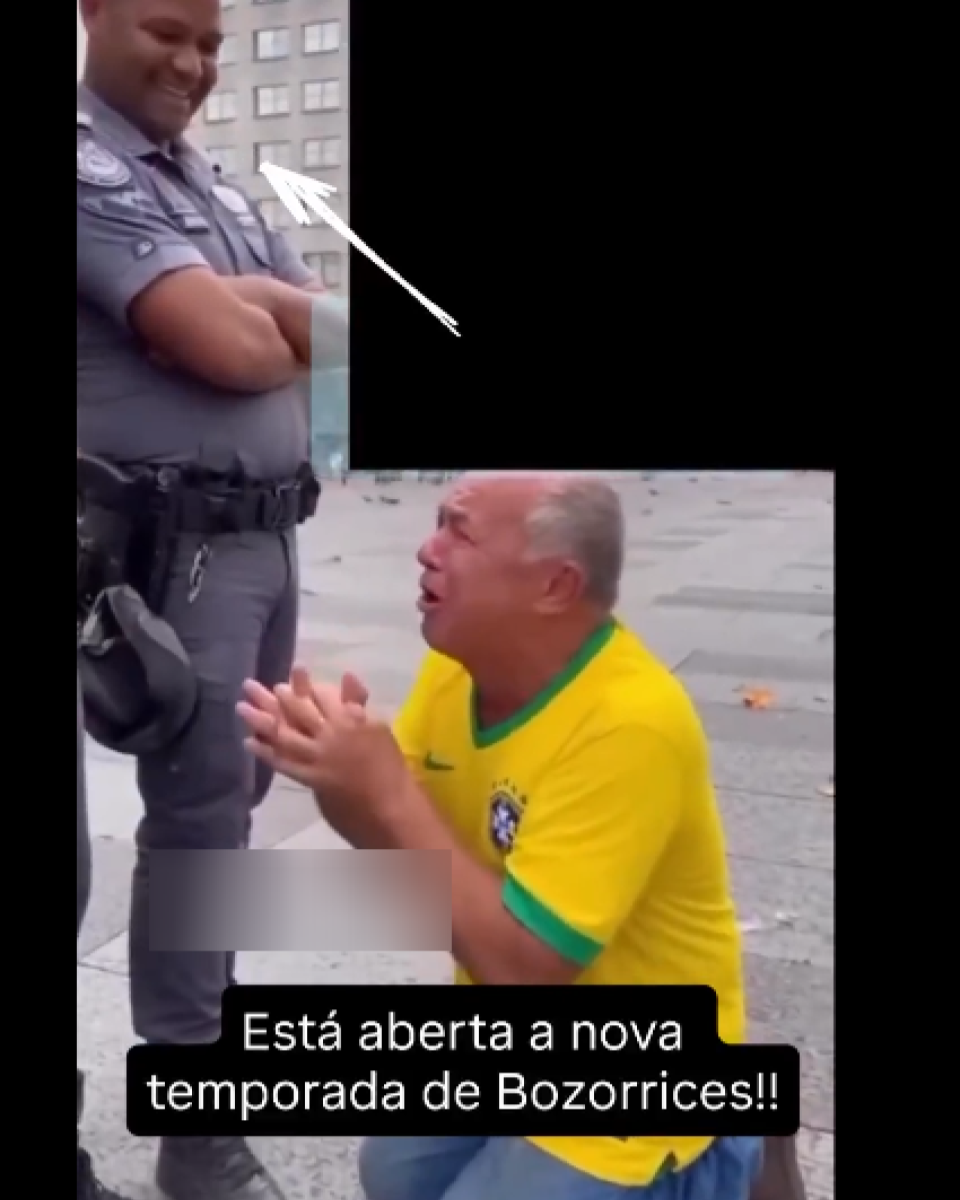 A imagem mostra um homem de pele clara, com cabelos curtos e grisalhos, ajoelhado no chão enquanto gesticula com as mãos em direção a um policial. O agente, que é um homem de pele escura, usa uniforme cinza, colete tático, cinto com equipamentos e botas, permanecendo de pé com os braços cruzados. O cenário é uma área urbana ao ar livre, com edifícios ao fundo, e há textos sobrepostos na imagem.