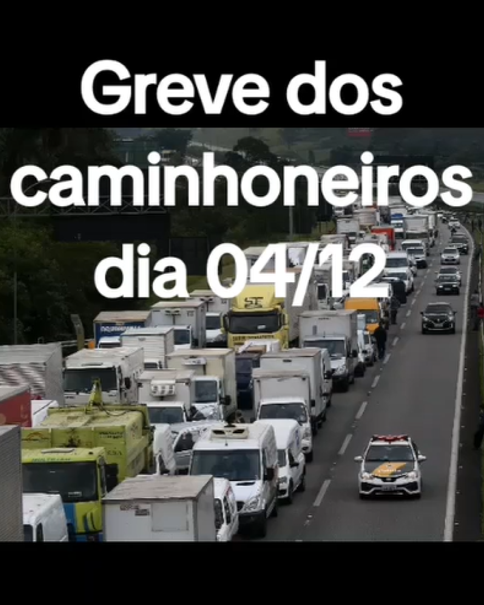 A imagem mostra uma rodovia com grande quantidade de caminhões e outros veículos comerciais parados em várias faixas, formando uma longa fila; à frente, aparece um carro branco caracterizado como viatura, com faixas amarelas no capô; no centro superior da imagem há um texto, em letras brancas, que diz ‘Greve dos caminhoneiros dia 04/12’.