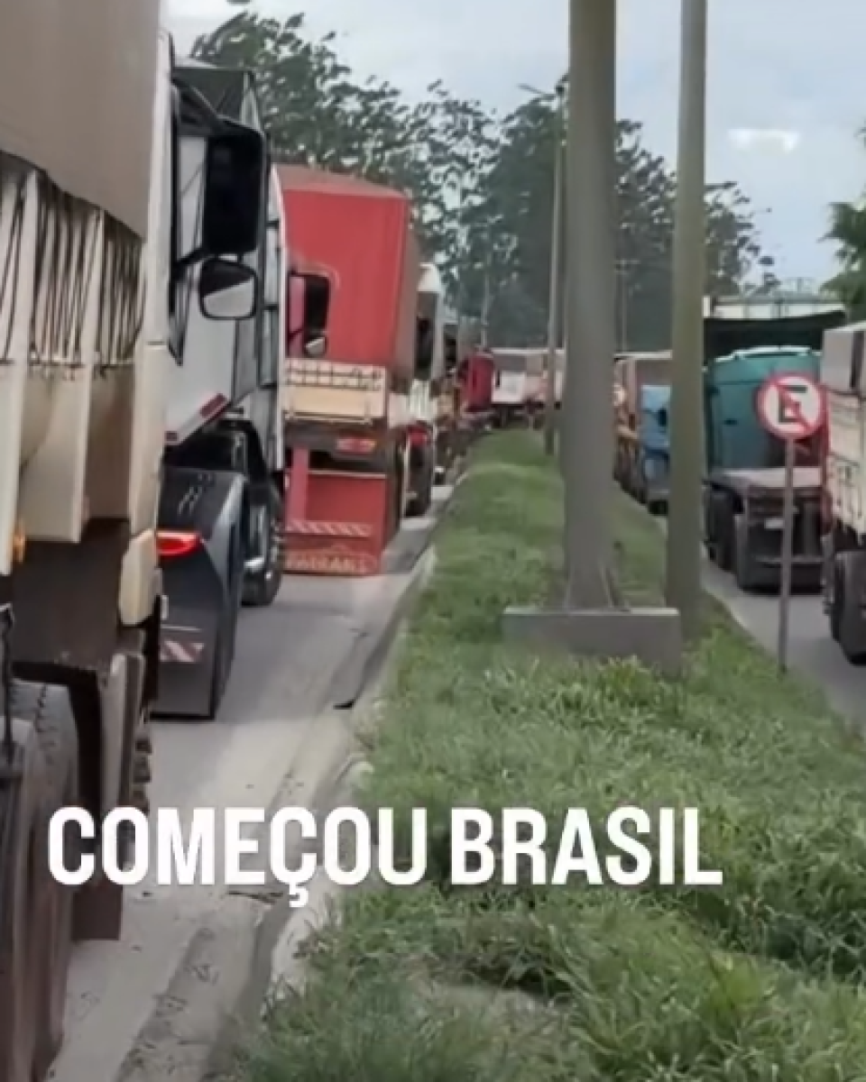 A imagem exibe uma fila densa e extensa de caminhões de grande porte parados em uma estrada. No canto inferior esquerdo da imagem, há uma sobreposição de texto em letras maiúsculas brancas que diz: 'COMEÇOU BRASIL'.