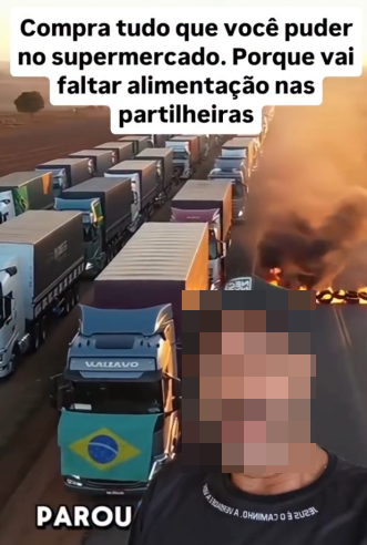 A imagem, gerada por IA, mostra uma fila de caminhões estacionados em uma estrada larga, alguns deles exibindo a bandeira do Brasil na dianteira; ao lado direito há chamas e fumaça escura subindo de uma área em combustão. Na parte inferior, aparece a foto de uma pessoa com o rosto pixelado, pele de tom médio e vestindo uma camisa escura e um boné escuro. Há textos sobrepostos na imagem, incluindo a frase ‘Compra tudo que você puder no supermercado. Porque vai faltar alimentação nas partilheiras’.