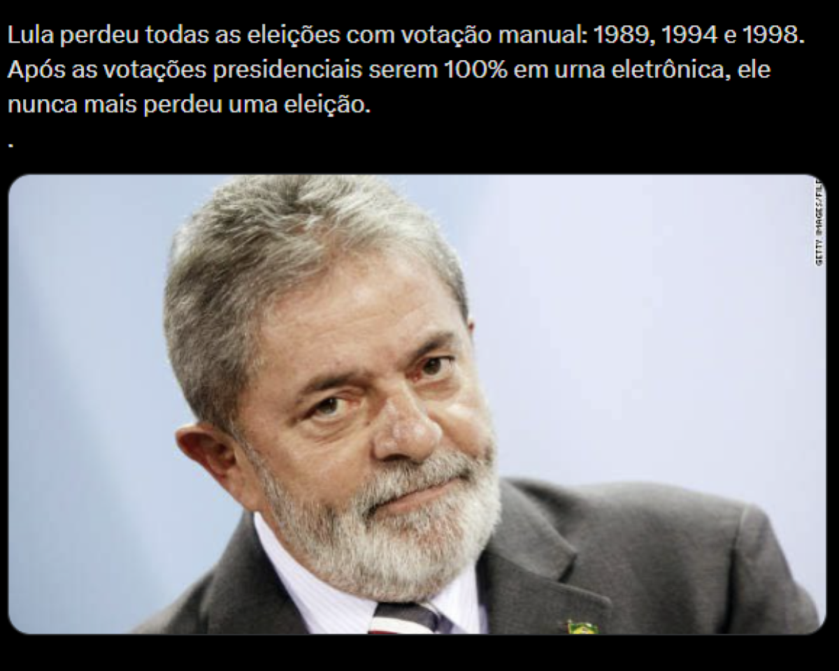 A imagem tem fundo preto na parte superior, onde há um texto escrito em branco: “Lula perdeu todas as eleições com votação manual: 1989, 1994 e 1998. Após as votações presidenciais serem 100% em urna eletrônica, ele nunca mais perdeu uma eleição.” Logo abaixo do texto, ocupa a maior parte do espaço uma fotografia de um homem de pele clara, cabelos e barba grisalhos, usando terno escuro, camisa clara e gravata. Ele aparece em close, levemente inclinado para o lado, com expressão neutra, olhando para a frente. 