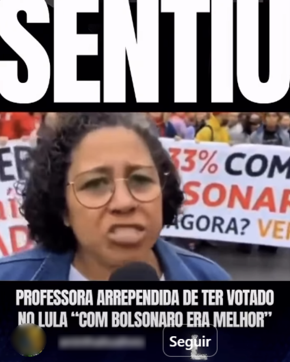 Imagem em formato vertical. No centro, há uma mulher em primeiro plano, com cabelo curto cacheado, usando óculos de armação redonda e uma jaqueta de cor azul. Ela segura um microfone próximo à boca, como se estivesse falando ou sendo entrevistada. Ao fundo, aparecem várias pessoas reunidas em uma manifestação, com faixas estendidas. Uma das faixas visíveis contém textos em letras grandes e coloridas, incluindo porcentagens e palavras em vermelho e preto, parcialmente encobertas pela figura em primeiro plano. Na parte superior da imagem, há uma faixa preta com a palavra ‘SENTIU’. Na parte inferior, também sobre uma faixa escura, há um texto em letras brancas que diz: ‘PROFESSORA ARREPENDIDA DE TER VOTADO NO LULA ‘COM BOLSONARO ERA MELHOR’’.