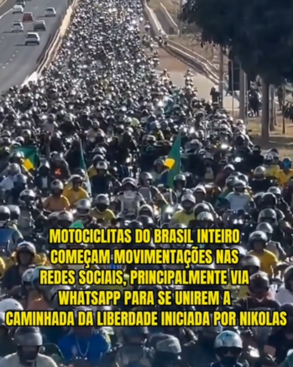 Imagem aérea mostra uma motociata enorme ocupando várias faixas de uma via, com motociclistas usando capacetes. No meio do grupo aparecem algumas bandeiras do Brasil. Sobre a imagem, há um texto grande em amarelo dizendo: ‘MOTOCICLITAS DO BRASIL INTEIRO COMEÇAM MOVIMENTAÇÕES NAS REDES SOCIAIS, PRINCIPALMENTE VIA WHATSAPP PARA SE UNIREM A CAMINHADA DA LIBERDADE INICIADA POR NIKOLAS.