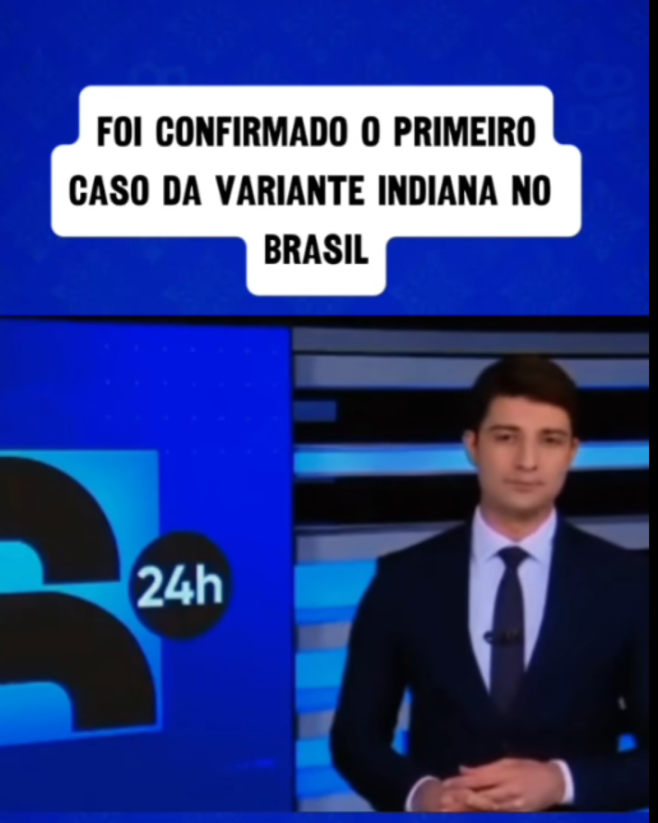 Apresentador de telejornal — homem de pele clara, cabelo curto castanho, vestindo terno escuro, camisa branca e gravata — aparece em estúdio com fundo azul e elementos gráficos do canal Record News. Na parte superior da imagem, há um texto que diz: ‘FOI CONFIRMADO O PRIMEIRO CASO DA VARIANTE INDIANA NO BRASIL’.