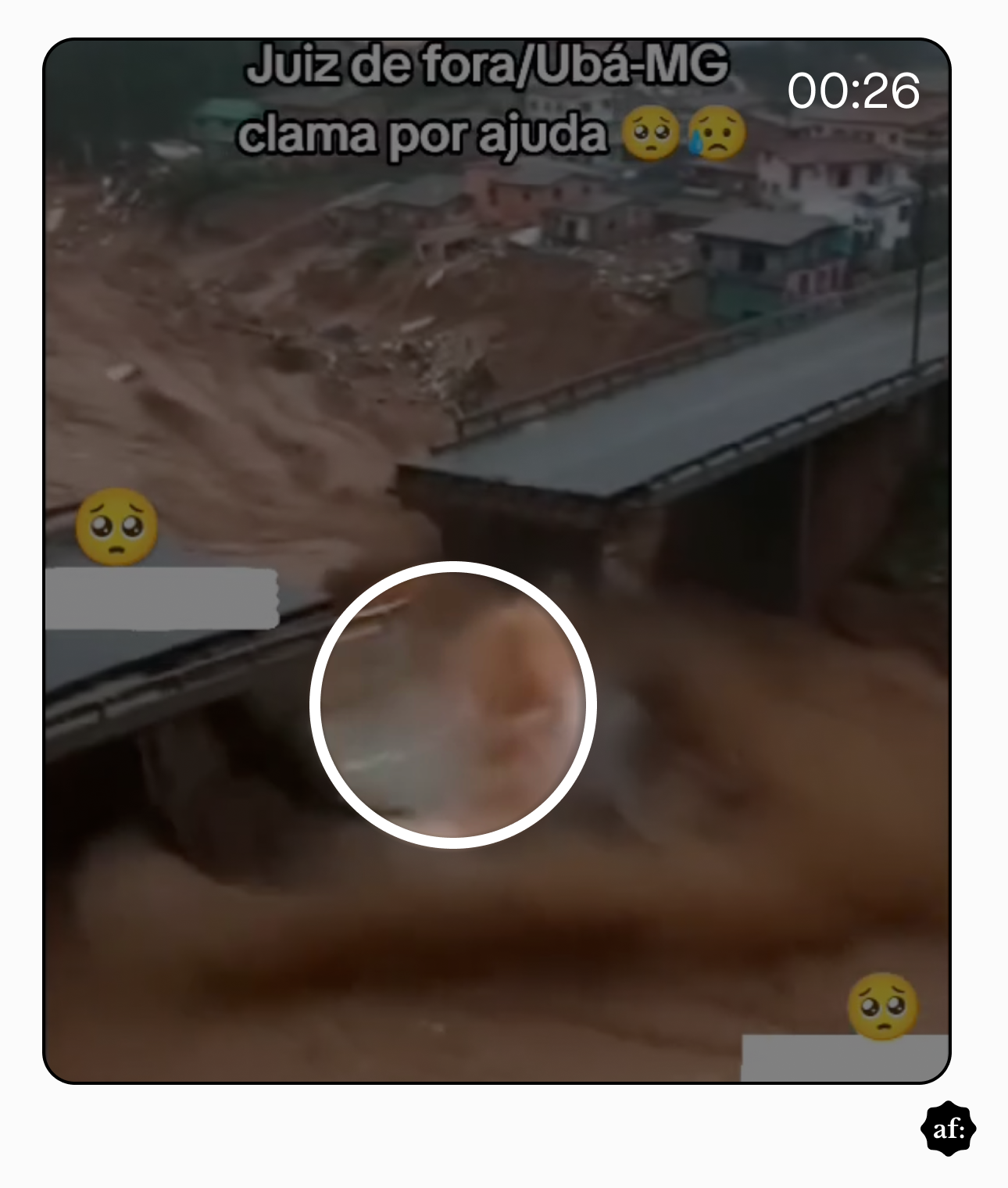 Imagem mostra uma área urbana com várias casas de alvenaria em encosta ao fundo e duas pontes de concreto atravessando um curso de água, enquanto uma forte enxurrada de lama marrom passa sob as estruturas, formando correnteza intensa e espuma. Um círculo branco destaca um ponto específico na água turva. Sobre a imagem, há um texto em destaque que diz: ‘Juiz de fora/Ubá-MG clama por ajuda’