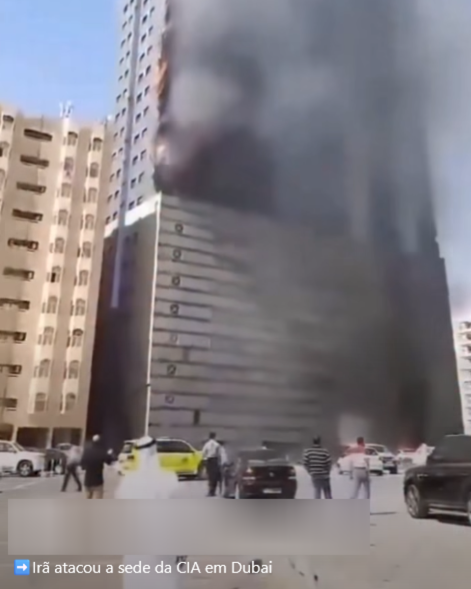 Post no Instagram mostra prédio alto envolto por fumaça escura, com chamas visíveis em alguns andares da fachada. No térreo, há carros estacionados e pessoas observando a cena à distância. Na parte inferior do vídeo, aparece a legenda: ‘Irã atacou a sede da CIA em Dubai’.