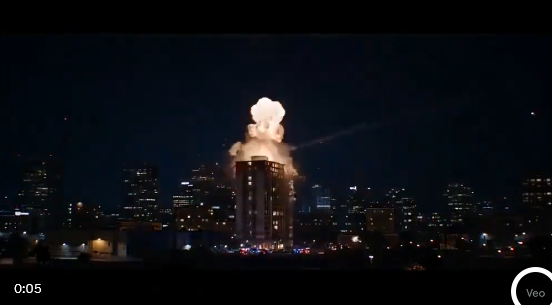 Imagem semelhante a anterior, com um míssil atingindo um prédio. Desta vez, há um destaque circular branco no canto inferior direito para mostar o logotipo do Veo.