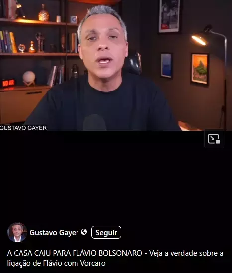 A imagem mostra uma captura de tela de uma publicação no Facebook. Na parte superior, aparece um vídeo de Gustavo Gayer, um homem de cabelos curtos e grisalhos, usando camiseta preta e sentado em frente a uma câmera. Ele está em um ambiente interno com estantes de madeira ao fundo, contendo livros e objetos decorativos. À esquerda, há uma placa iluminada com a inscrição 'NO AR'. À direita, há um abajur aceso e quadros pendurados na parede. No canto inferior esquerdo do vídeo, aparece o nome 'GUSTAVO GAYER'. Abaixo do vídeo, há uma faixa preta. Na parte inferior da imagem, aparece a identificação do perfil 'Gustavo Gayer', acompanhada de um ícone de verificação e de um botão com a palavra 'Seguir'. Logo abaixo, está o texto da publicação: 'A CASA CAIU PARA FLÁVIO BOLSONARO - Veja a verdade sobre a ligação de Flávio com Vorcaro'.