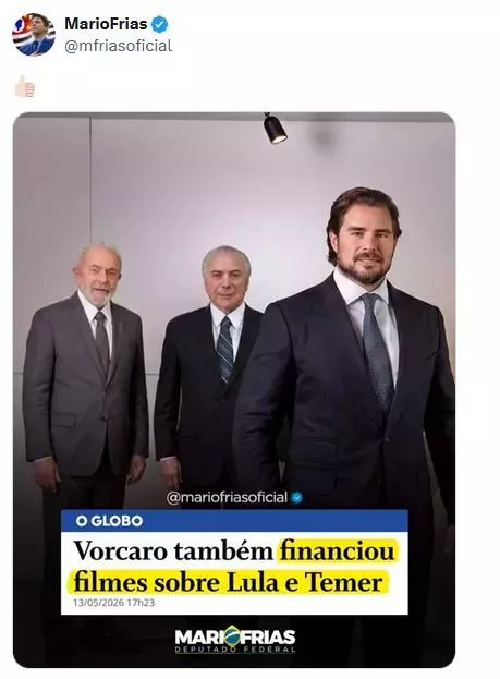 A imagem mostra uma captura de tela de uma publicação em rede social. No topo, aparece o nome ‘MarioFrias’ em negrito com um símbolo azul de verificação ao lado e, abaixo, o nome de usuário ‘@mfriasoficial’. Logo abaixo há um emoji de polegar para cima. A publicação contém uma imagem mostrando o presidente Lula, o ex-presidente Michel Temer e o banqueiro Daniel Vorcaro. Eles usam ternos escuros em um ambiente interno de paredes claras. Vorcaro está em primeiro plano, à direita, olhando para a câmera. Atrás dele, à esquerda, aparecem primeiro Temer e Lula posicionados lado a lado. No teto, acima deles, há um pequeno refletor preto apontado para baixo. Na parte inferior da foto há uma faixa com o logotipo ‘O GLOBO’ em branco sobre fundo azul e, abaixo, um texto em preto sobre fundo branco e amarelo que diz: ‘Vorcaro também financiou filmes sobre Lula e Temer’. A data ‘13/05/2026 17h23’ aparece em letras pequenas abaixo do texto. Mais abaixo está escrito ‘MARIO FRIAS DEPUTADO FEDERAL’. Também aparece o texto ‘@mariofriasoficial’ sobre a imagem, acompanhado de um símbolo azul de verificação.