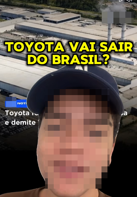 Uma imagem exibe em primeiro plano uma pessoa de pele clara com o rosto totalmente coberto por um efeito de pixelização, usando um boné escuro e parte de uma blusa marrom visível na base. Ao fundo, há uma fotografia aérea de um extenso complexo industrial com grandes galpões e chaminés que emitem fumaça, além de um pequeno retângulo cinza borrado no canto superior direito. Sobreposta ao centro da composição, destaca-se a pergunta em grandes letras amarelas com contorno preto: 'TOYOTA VAI SAIR DO BRASIL?'. À esquerda, parcialmente encobertos pela figura da pessoa, notam-se um pequeno retângulo azul e trechos incompletos de um texto em branco onde é possível ler as palavras 'Toyota' e 'e demite'. 