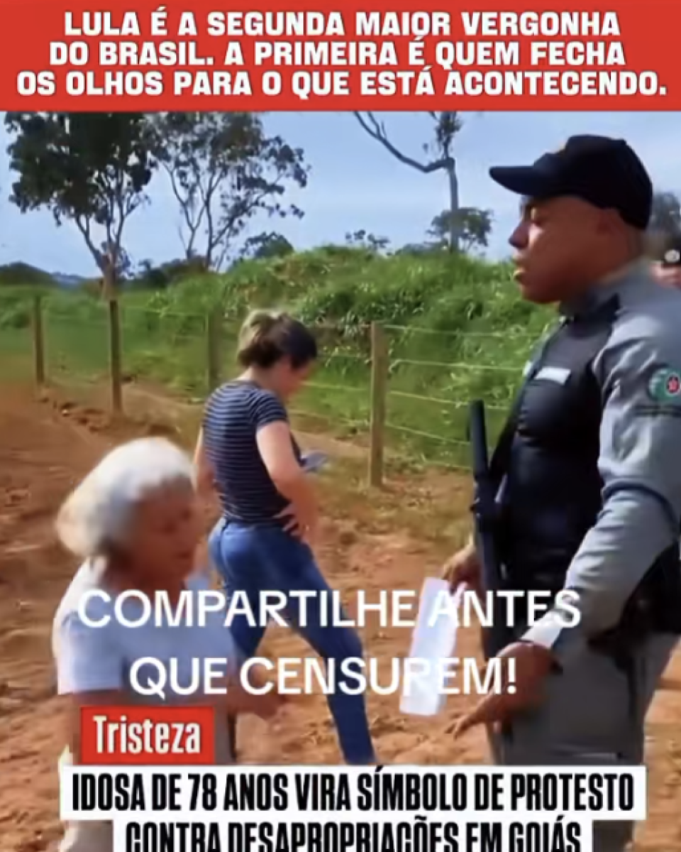 A imagem é uma captura de vídeo em formato vertical com faixas de texto na parte superior, central e inferior. No topo, sobre uma faixa vermelha, há um texto em letras brancas e maiúsculas que diz: 'LULA É A SEGUNDA MAIOR VERGONHA DO BRASIL. A PRIMEIRA É QUEM FECHA OS OLHOS PARA O QUE ESTÁ ACONTECENDO.'. A cena principal mostra uma estrada de terra cercada por uma cerca de arame e vegetação verde ao fundo, com árvores espalhadas sob um céu claro. À direita da imagem está um policial militar fardado, usando boné preto, uniforme cinza e colete tático escuro. Ele segura uma folha de papel em uma das mãos e um equipamento preso ao colete é visível na parte frontal do corpo. À esquerda, uma mulher idosa de cabelos brancos, vestindo uma camiseta branca, aparece em movimento diante do policial. Ao centro, um pouco mais ao fundo, há outra mulher, de cabelos presos, usando uma camiseta listrada em azul e branco e calça jeans, olhando para um celular que segura nas mãos. Sobre a parte central da imagem há um texto em letras brancas e maiúsculas que diz: 'COMPARTILHE ANTES QUE CENSUREM!'. Na parte inferior, sobre uma faixa branca, há um selo vermelho com a palavra 'Tristeza' em branco. Ao lado e abaixo dele, em letras pretas e maiúsculas, está escrito: 'IDOSA DE 78 ANOS VIRA SÍMBOLO DE PROTESTO CONTRA DESAPROPRIAÇÕES EM GOIÁS'. 