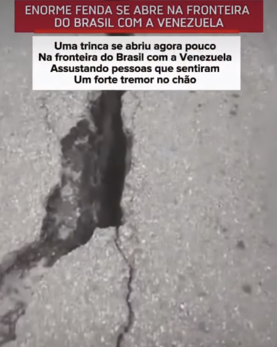 A imagem mostra um trecho de asfalto cinza com uma rachadura longa e escura que atravessa a pista na vertical. A abertura é mais larga na parte superior e vai se estreitando conforme desce, com pequenas fissuras se ramificando ao redor. O enquadramento é feito de cima para baixo, mostrando apenas o pavimento, sem pessoas ou outros elementos visíveis. Na parte superior da imagem há uma faixa vermelha com o texto em letras brancas: 'ENORME FENDA SE ABRE NA FRONTEIRA DO BRASIL COM A VENEZUELA'. Logo abaixo, sobre um retângulo branco, aparece outro texto em letras pretas distribuído em quatro linhas: 'Uma trinca se abriu agora pouco', 'Na fronteira do Brasil com a Venezuela', 'Assustando pessoas que sentiram' e 'Um forte tremor no chão'.