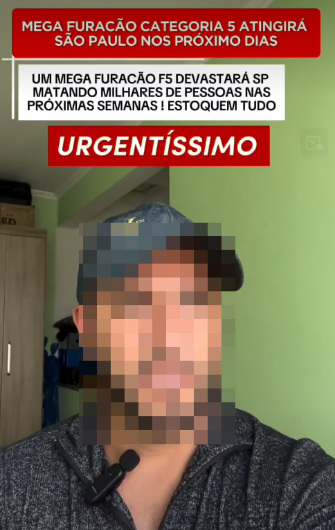 A imagem, que parece uma captura de tela de um vídeo de rede social, mostra um homem de pele de tom médio, com barba e o rosto pixelizado (censurado) em primeiro plano. Ele usa um boné cinza escuro e um casaco texturizado com zíper, com um pequeno microfone de lapela preto preso. Ele está em um ambiente interno com um armário de madeira marrom e uma parede pintada de verde-limão ao fundo. Sobrepostas à imagem, há três mensagens de texto alarmistas em português: no topo, uma barra vermelha diz: ‘MEGA FURACÃO CATEGORIA 5 ATINGIRÁ SÃO PAULO NOS PRÓXIMOS DIAS’; abaixo dela, uma caixa branca com texto preto afirma: ‘UM MEGA FURACÃO F5 DEVASTARÁ SP MATANDO MILHARES DE PESSOAS NAS PRÓXIMAS SEMANAS ! ESTOQUEM TUDO’; e no centro, outra barra vermelha contém a palavra ‘URGENTÍSSIMO’.