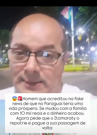 Alt text: homem branco adulto, grava vídeo em formato de selfie. Ao fundo, é possível ver uma praça com uma bandeira do Paraguai. Em volta há árvores e luzes. Uma caixa branca de texto diz: 'Homem que acreditou na fake news de que no Paraguai teria uma vida próspera. Se mudou com a família com 10 mil reais e o dinheiro acabou. Agora ele pede que o Itamaraty o repatrie e pague a sua passagem de volta'