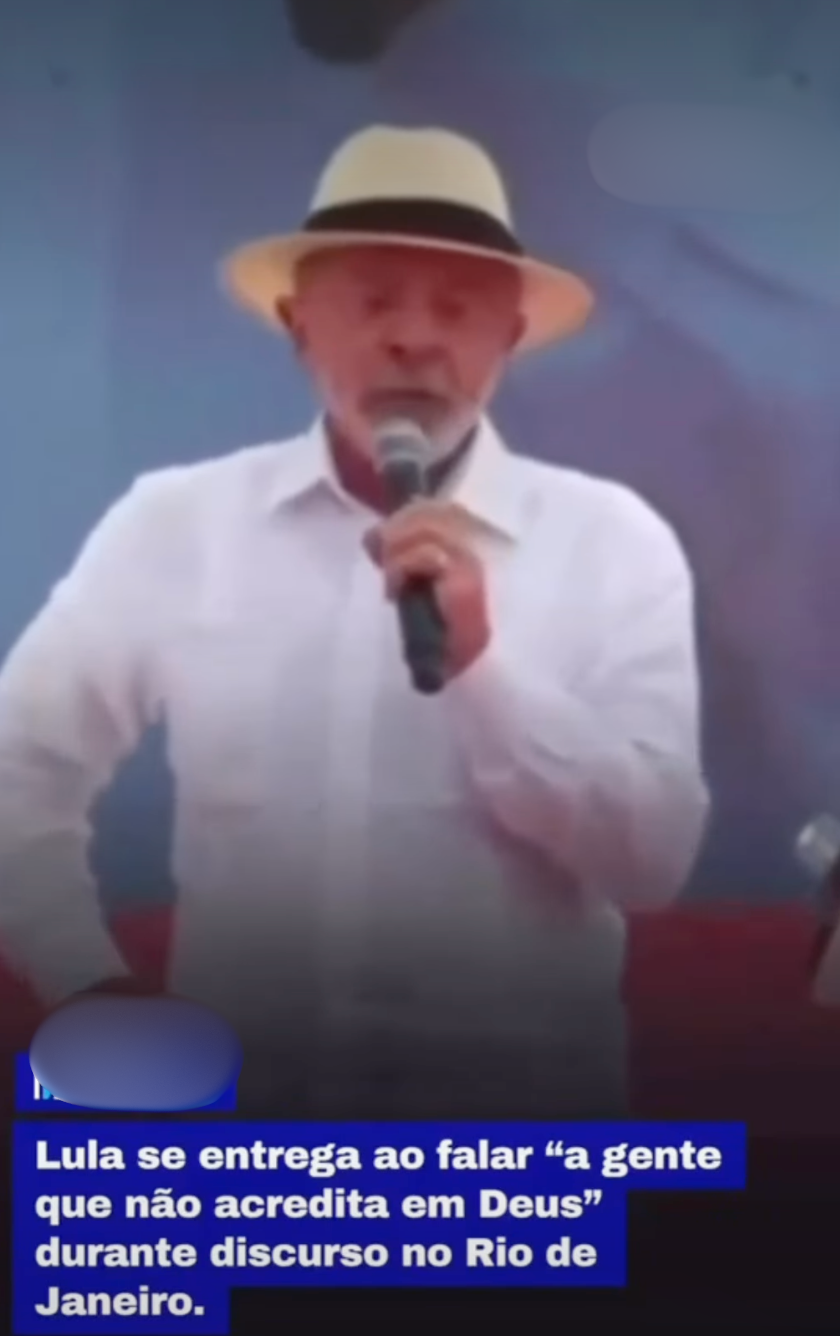 Uma imagem mostra Luiz Inácio Lula da Silva, com um chapéu de palha e camisa branca de botão, segurando um microfone e falando. Uma legenda azul na parte inferior contém o texto: 'Lula se entrega ao falar 'a gente que não acredita em Deus' durante discurso no Rio de Janeiro.' Um borrão azul encobre um logotipo na parte inferior esquerda.