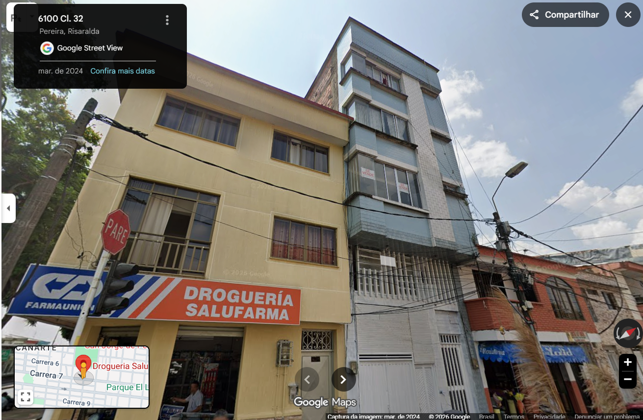 Captura de tela da interface do Google Street View mostrando uma rua residencial e comercial. Em primeiro plano, destaca-se um prédio amarelo de três andares onde funciona no térreo uma farmácia com letreiro nas cores azul, laranja e branca escrito ‘Droguería Salufarma’ e ‘Farmaunion’, além de uma placa octogonal vermelha de’PARE’. Ao lado, há outro prédio mais alto e estreito de cor azul-claro com placas de ‘Se Vende’ nas janelas. No canto superior esquerdo há uma caixa preta com a localização ‘6100 Cl. 32, Pereira, Risaralda’, e no canto inferior esquerdo aparece a miniatura de um mapa com o pin da farmácia.