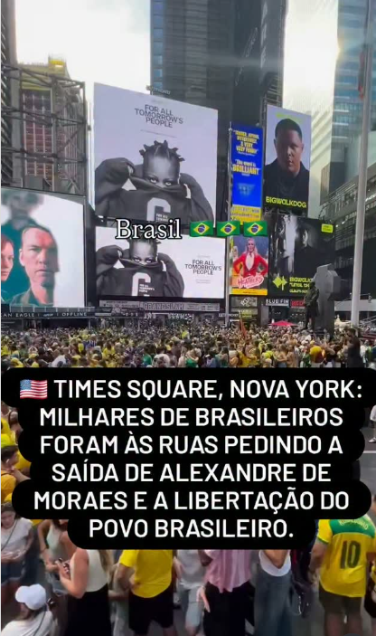Imagem vertical de uma multidão ocupando a Times Square, em Nova York, com muitas pessoas usando roupas nas cores verde e amarelo e algumas segurando bandeiras do Brasil. Ao fundo, grandes painéis digitais exibem anúncios e imagens, enquanto uma faixa sobreposta à foto afirma que milhares de brasileiros foram às ruas pedindo a saída de Alexandre de Moraes e a libertação do povo brasileiro.