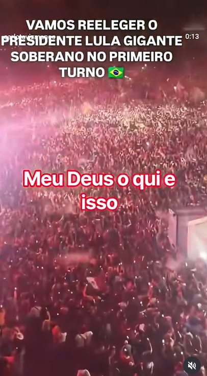Alt text: print de vídeo postado nas redes sociais que mostra multidão aglomerada em um local durante a noite, com luzes ao redor. Bandeiras do México aparecem pela imagem. Está escrito: Vamos reeleger Lula gigante soberano no primeiro turno