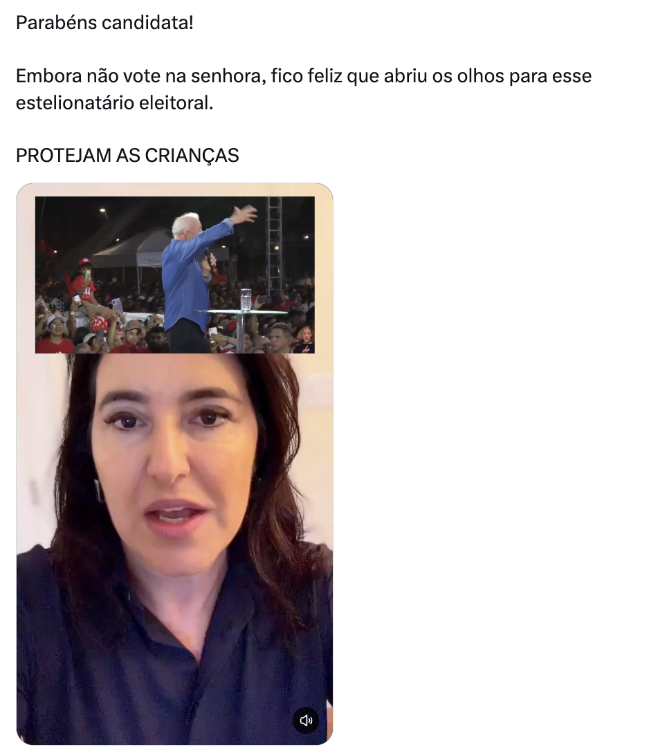 Captura de tela de uma publicação de rede social contendo texto e vídeo embutido. Na parte superior, há uma mensagem escrita: ‘Parabéns candidata! Embora não vote na senhora, fico feliz que abriu os olhos para esse estelionatário eleitoral. PROTEJAM AS CRIANÇAS’. Abaixo do texto, há um vídeo dividido em duas partes: na metade superior, um homem de pele clara, cabelos brancos e camisa azul de mangas compridas aparece em pé sobre um palco, com o braço esquerdo estendido à frente, falando ao microfone diante de uma multidão vestida predominantemente de vermelho; na metade inferior, uma mulher de pele clara, olhos castanhos e cabelos escuros na altura dos ombros, vestindo uma camisa escura de colarinho, aparece em primeiro plano olhando para a câmera.