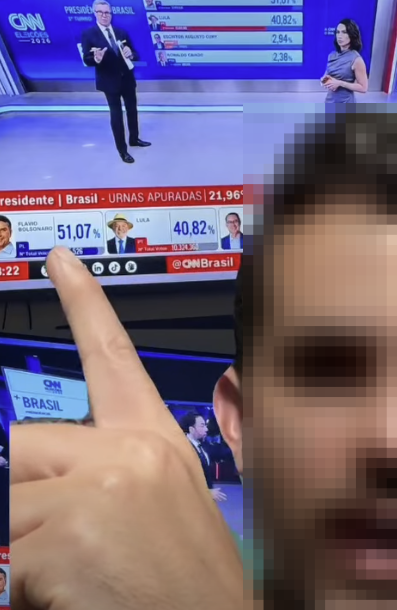 A imagem mostra uma pessoa com o rosto pixelado em primeiro plano, apontando com o dedo para uma televisão. Na tela da televisão, aparece uma transmissão da CNN Brasil sobre a apuração das eleições presidenciais, com um apresentador e uma apresentadora no estúdio. Um gráfico exibe os resultados, com Jair Bolsonaro com 51,07% e Lula com 40,82%, além de outros candidatos com percentuais menores. Na parte superior da tela, também aparecem outros números da apuração, incluindo 40,82%, 2,94% e 2,38%.